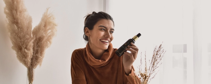 Mulher sorridente segurando frasco de protudo da Via Aroma