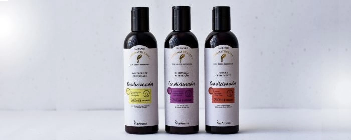 Três frascos de condicionador Via Aroma e um fundo branco